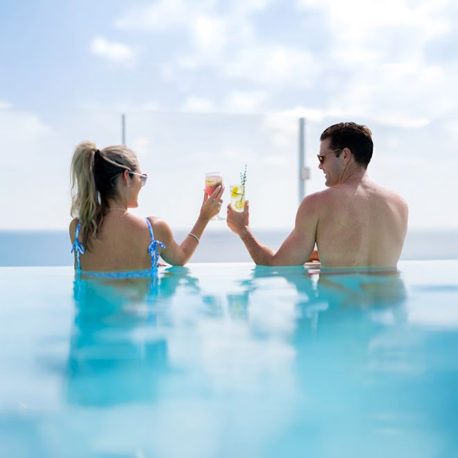 Cuplu cu cocktailuri la marginea piscinei