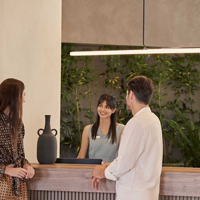 a Couple of Guests at the Reception Desk Talking to a Team Member