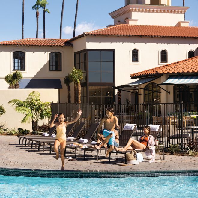 Kids Jumping on the Pool and a Woman Laying on a Lounge Chair in Outdoor Pool Area