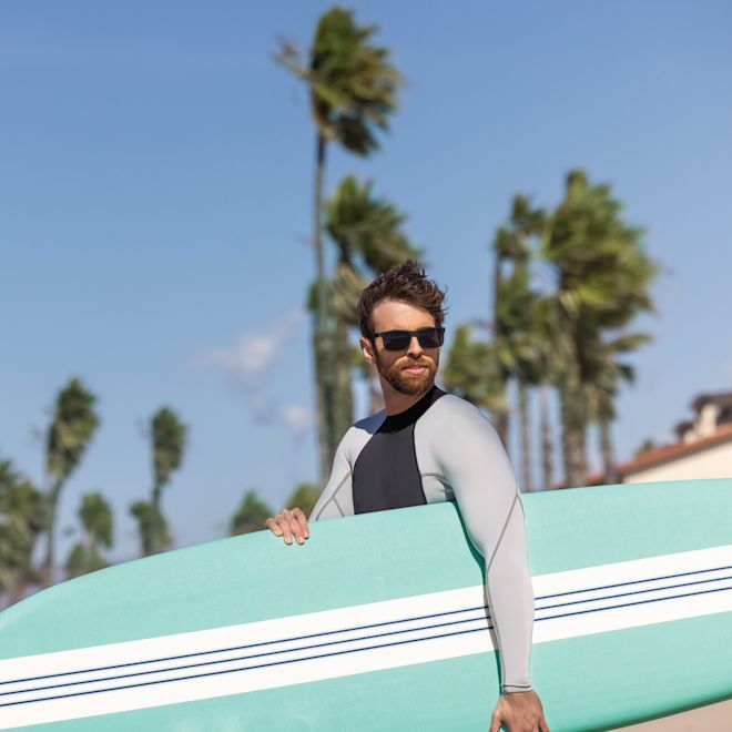 Man Holding a Surfboard at the Beach