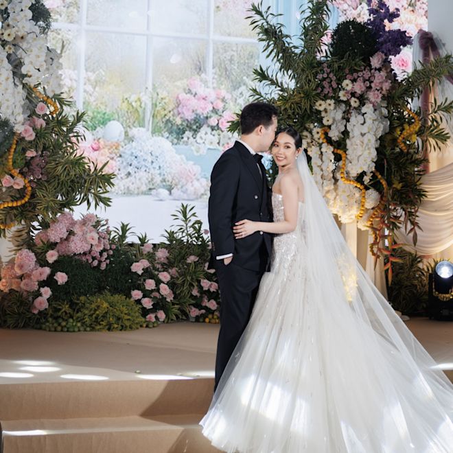 花のアレンジメントの隣に立つ新郎新婦