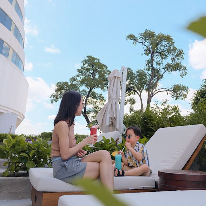 デッキチェアでドリンクを片手にくつろぐ母親と少年