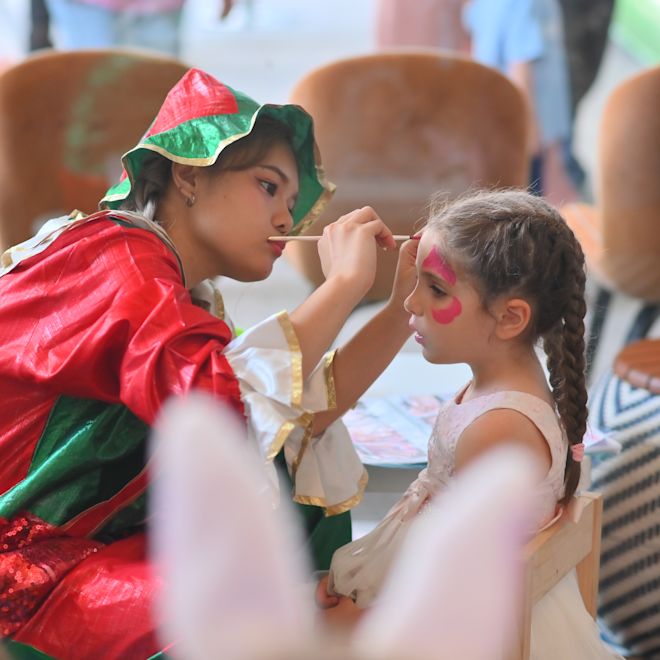 ピエロの衣装を着た女性が顔を描く若い女性