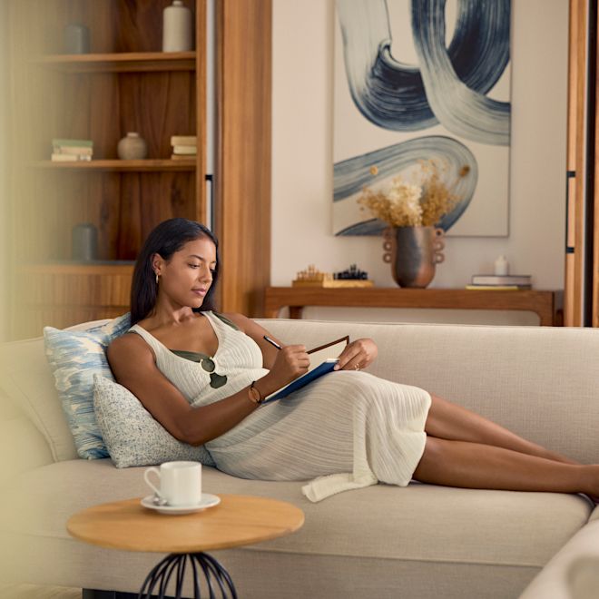 سيدة تسترخي على الأريكة داخل الجناح وتكتب في دفتر ملاحظات
