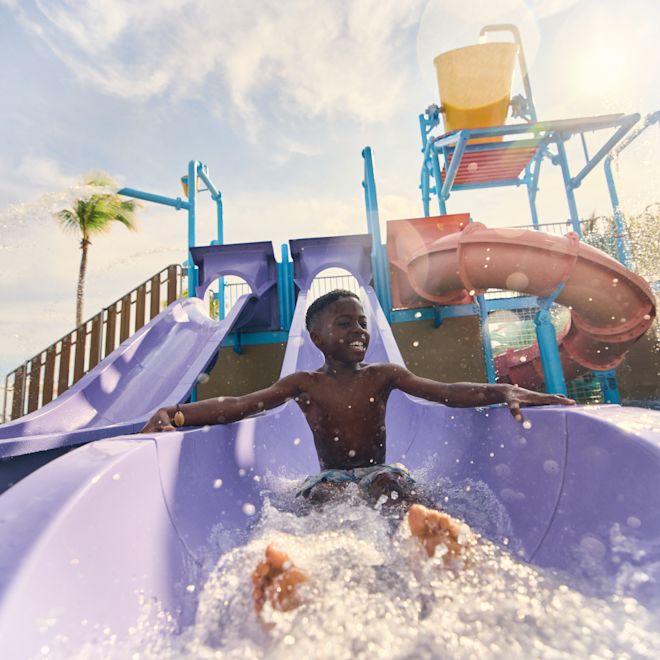 스플래시 존에서 거대한 워터슬라이드를 따라 달리는 소년