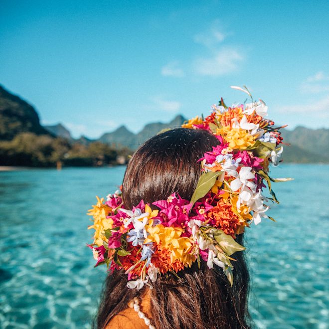 青い海を眺めながら、明るい色の花冠を身につけた女性