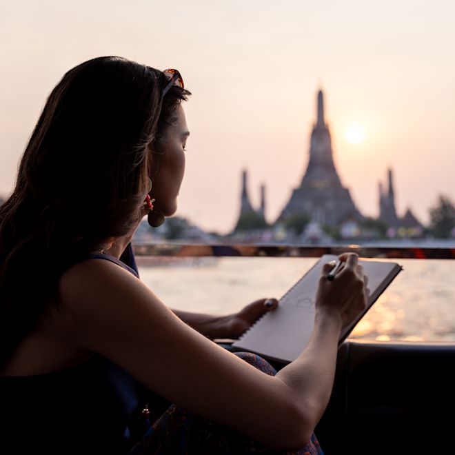 ボート乗り場から夕暮れの街を描く女性