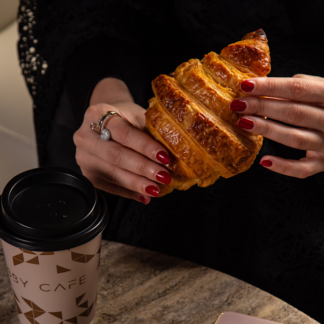 Woman Having Croissant and Coffee at the Terrace by Lobby Cafe