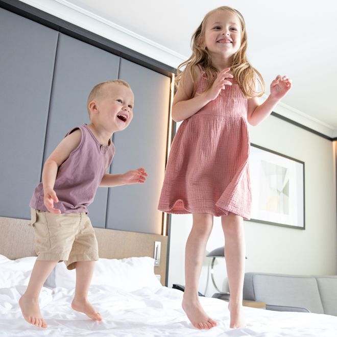 Kids Jumping on a Bed in a Guest Room