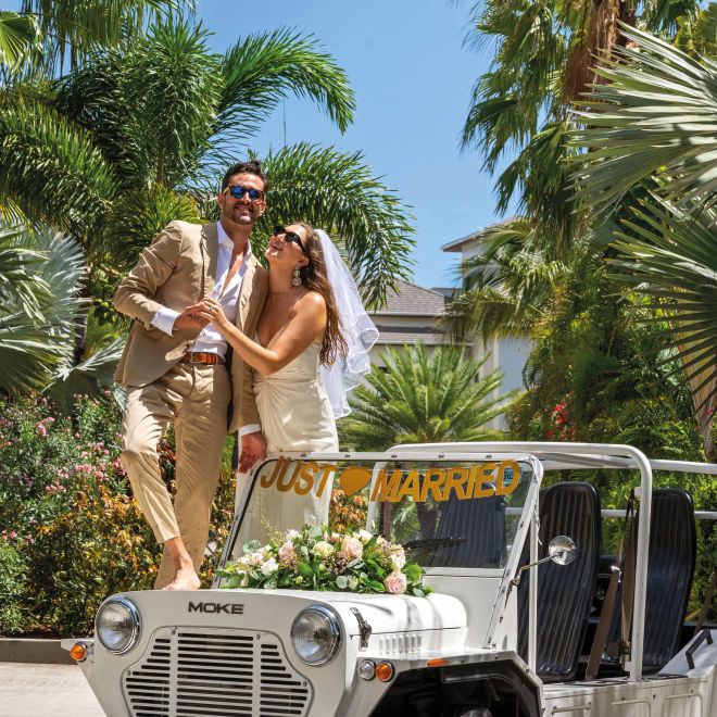 Couple standing on just married jeep