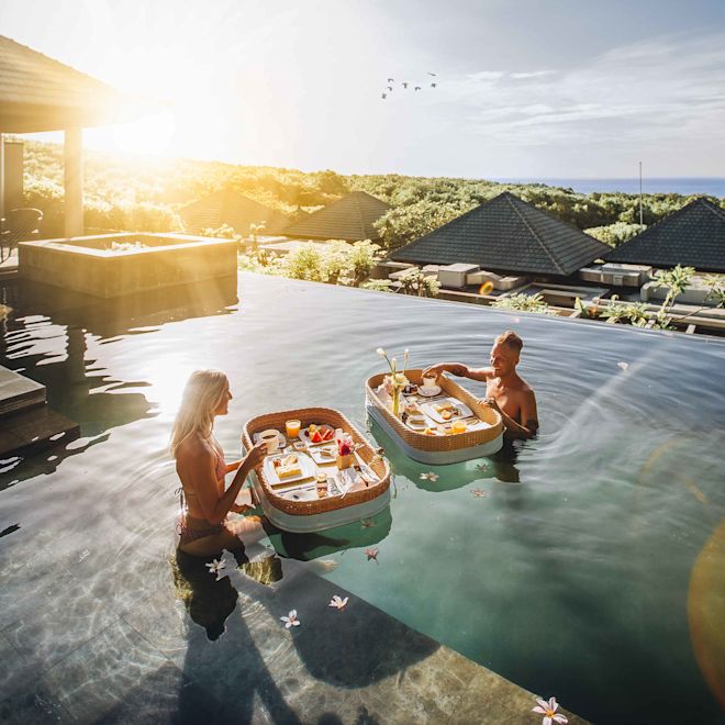 Woman and man having a floating breakfast in villa outdoor pool