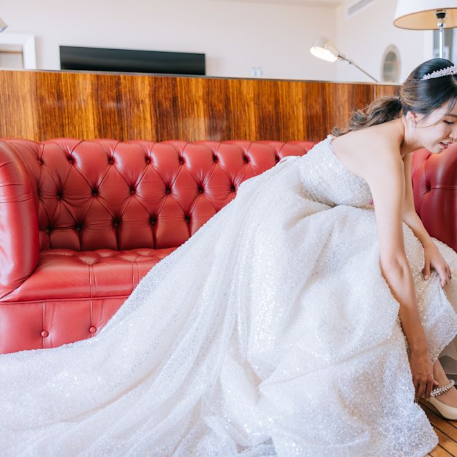 bride in her wedding dress putting on her shoes
