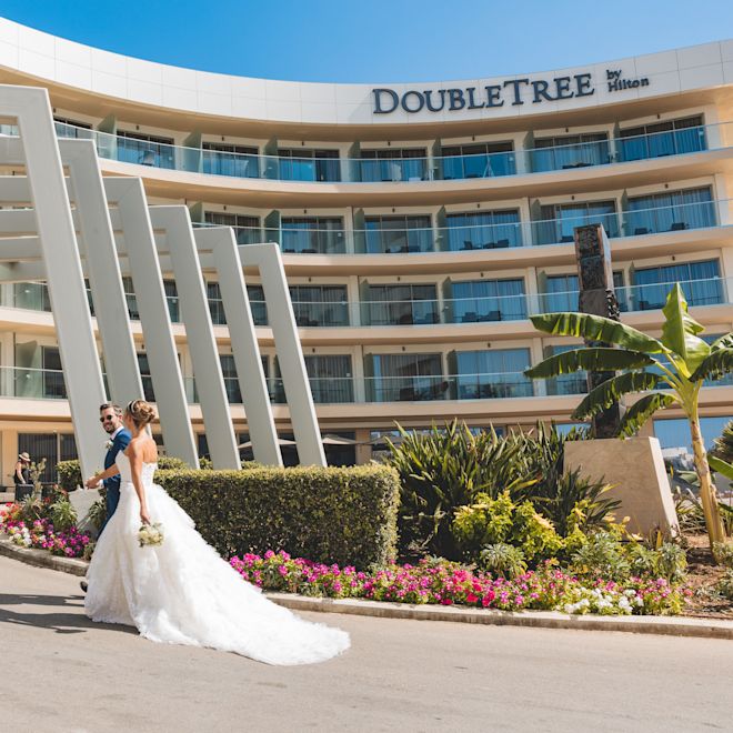 Mersul miresei și mirelui în fața exteriorului hotelului