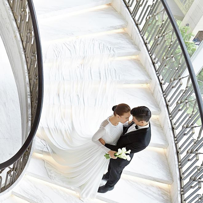 A wedding couple holding each other on the spiral staircase