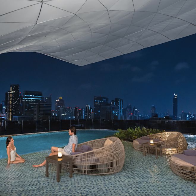 Man and woman relaxing by outdoor pool with city skyline