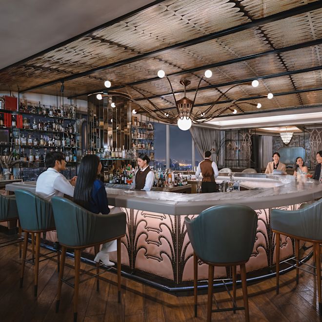 Bar area with several people sitting on stools and bar staff working