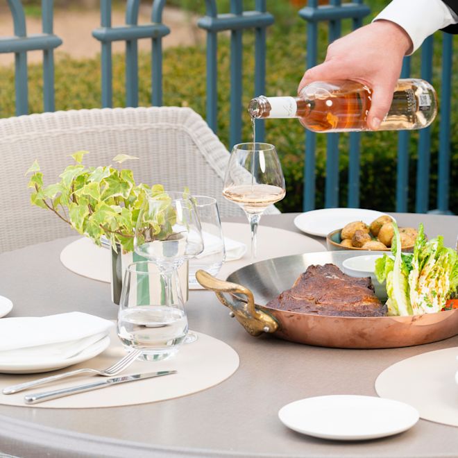 un bărbat care toarnă vinul într-un pahar în timp ce ia masa la restaurantul La Veranda