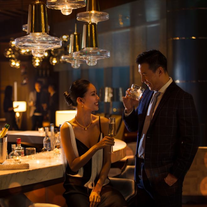 Couple Having Drinks in Bar Lounge with Bartender Standing Behind Bar Counter