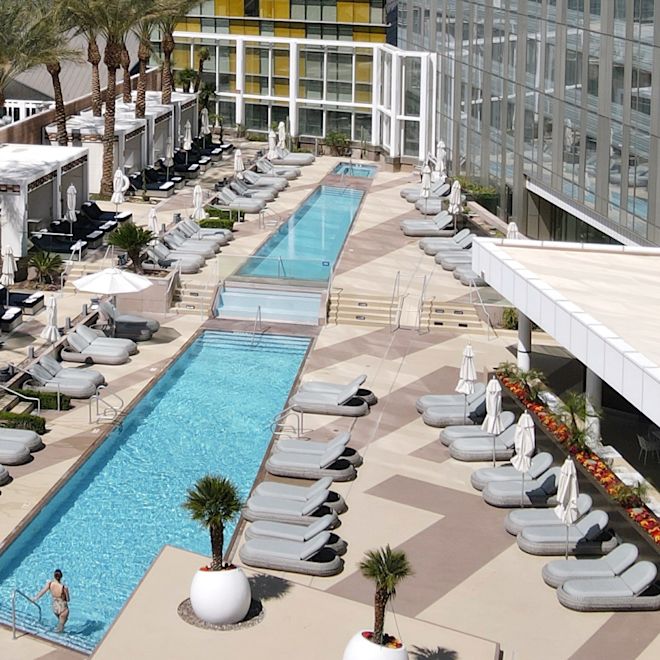 woman Stepping into an Outdoor Pool Surrounded by Lounge Chairs
