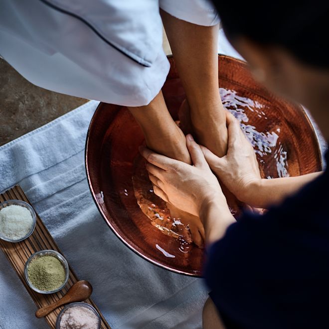 Client avec les pieds dans un bol de liquide, un membre du personnel offrant un massage