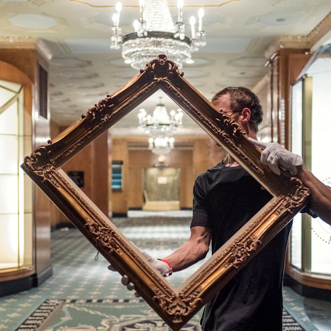a man carrying a restored picture frame in the Waldorf Astoria New York