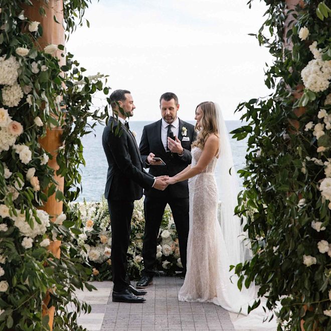 novia y novio se casan bajo un dosel de flores