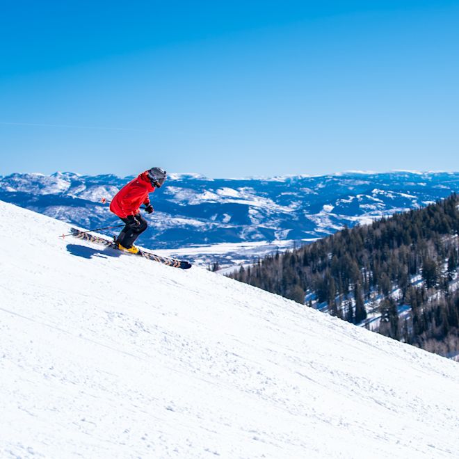 o persoană care schiează pe o pantă de munte înzăpezită