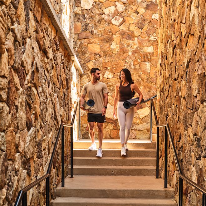 Un cuplu care ține saltele de Yoga coboară pe un set de scări