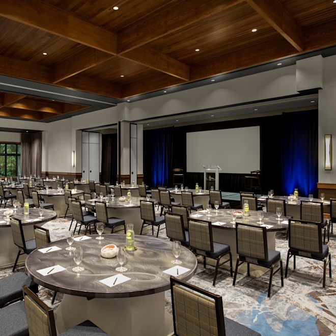 Cumberland Ballroom with round tables setup facing the front of the room and a large projector screen.