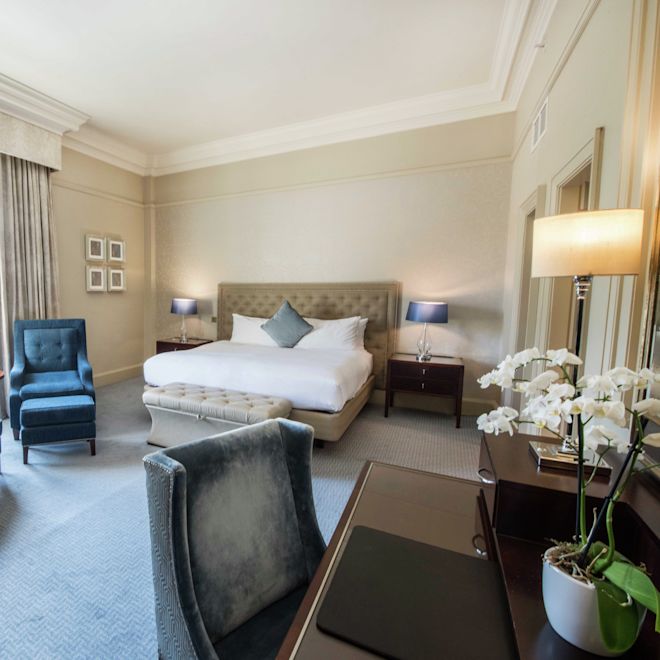 Bed in room with chairs and workdesk