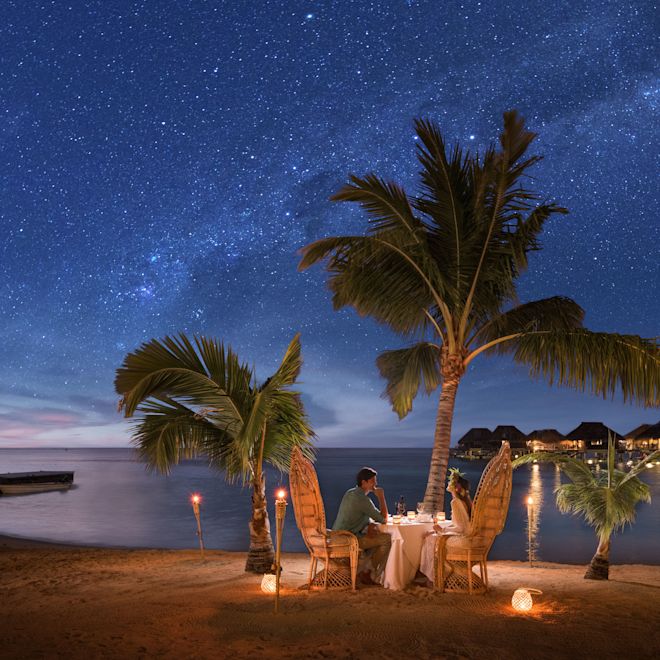 プライベートビーチでロマンチックなディナーを楽しむカップル