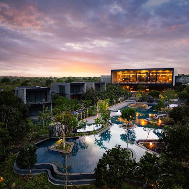Vista de la fachada del hotel y del área de la piscina por la noche