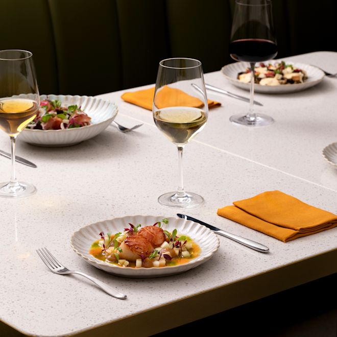 Plato de vieiras y copas de vino sobre una mesa en Park Corner Brasserie