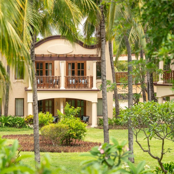 Hotel exterior visible through trees, with view of guest room balconies