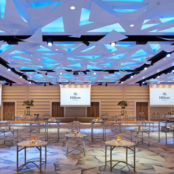 Cocktailbord och tre presentationsskärmar i mötesrummet som ställts in för bankett