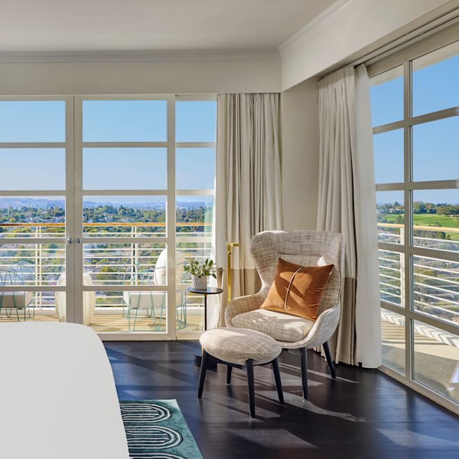 Sviitin vuode- ja oleskelualue, jossa suuret ikkunat