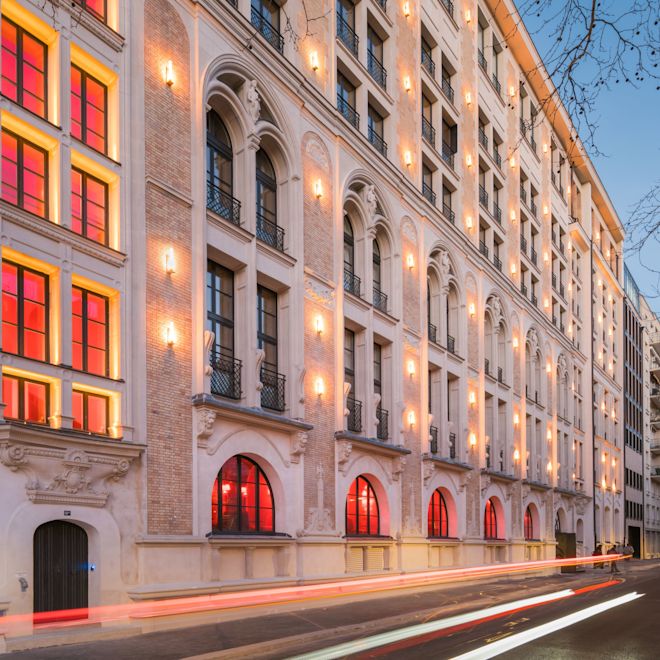 Exterior do hotel com janelas, iluminação e entrada