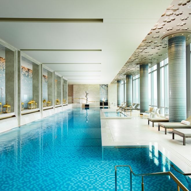 豪华的室内泳池，配有躺椅和可欣赏室外景观的落地窗