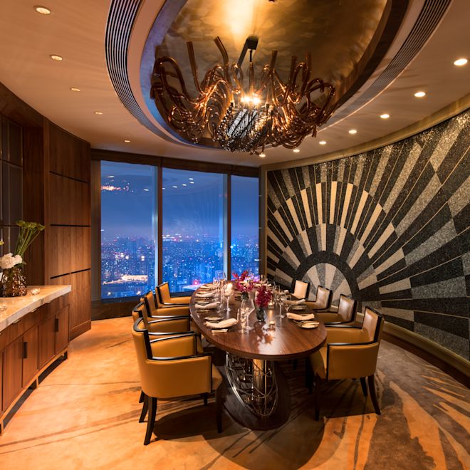 The Grill 餐厅私人包房，配有宽大餐桌、椅子、餐饮设施和落地窗，可欣赏夜间城市景观