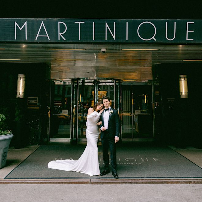 bride and groom standing in front of hotel entrance