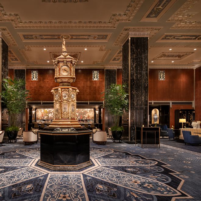 Luxurious lobby area with ornate clock, seating area, plants and pillars