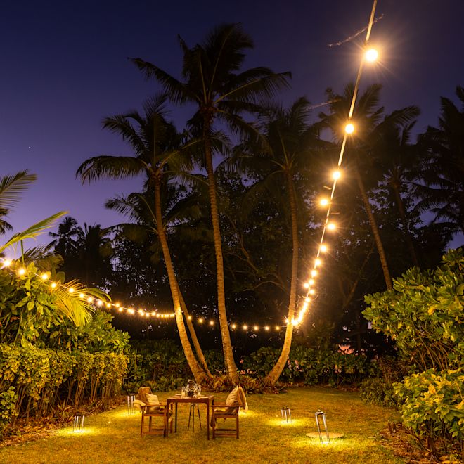 In der Villa Speisen mit Tisch, Stühlen, Märchenlicht und tropischen Bäumen