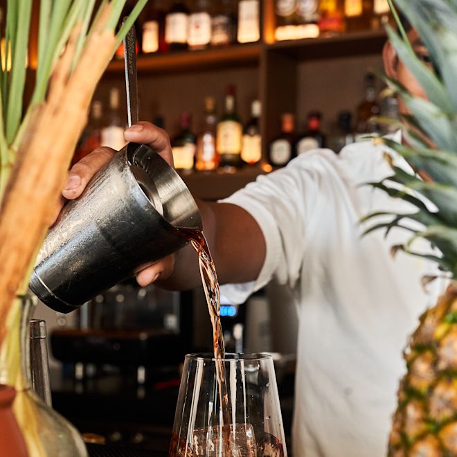 Barman Turnând o băutură pe un pahar la bar