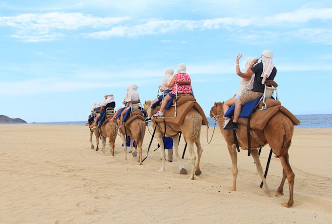 Grupo de personas montando camellos en el desierto