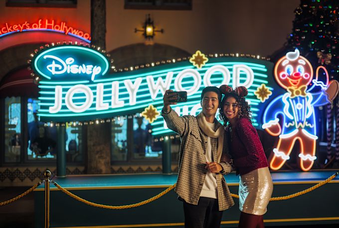 couple taking a photo in front of the disney jollywood sign