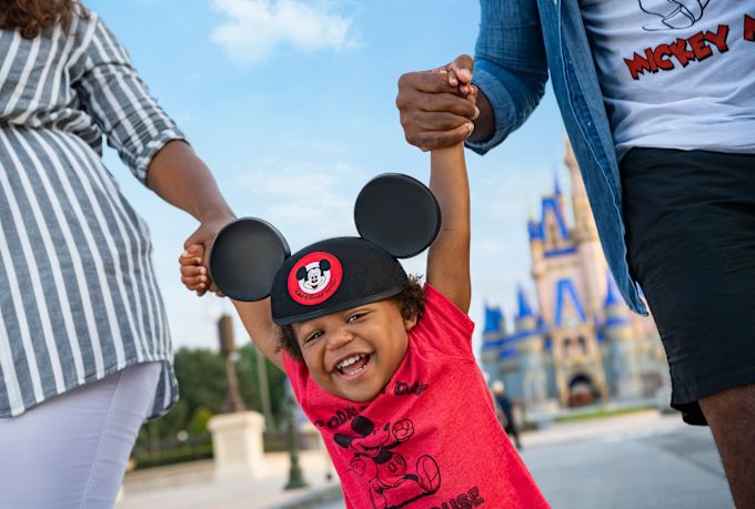 Boy wearing a Mickey Mouse hat with his parents at Disney World