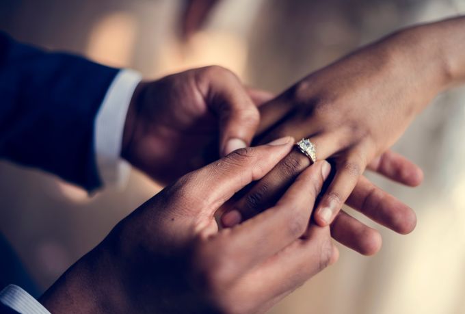 Closeup of man placing ring on woman's finger