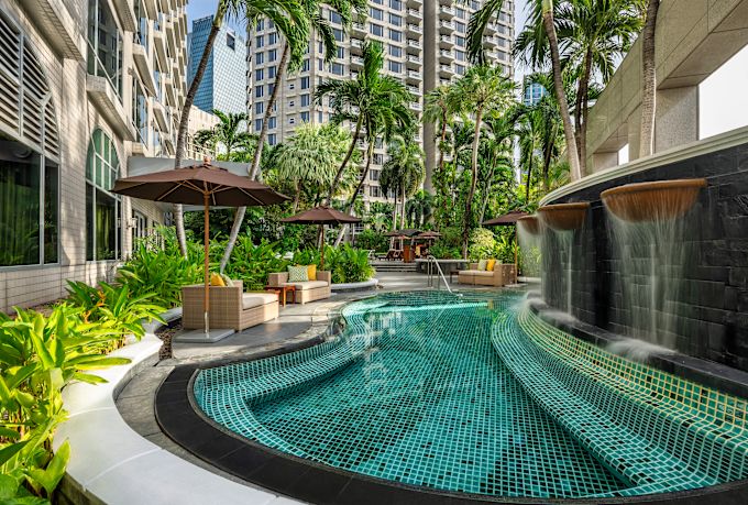 Outdoor Pool Area with Sitting Area under Umbrellas and Palm Trees