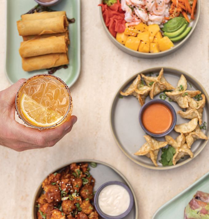 hand holding a drink aloft over a table of food