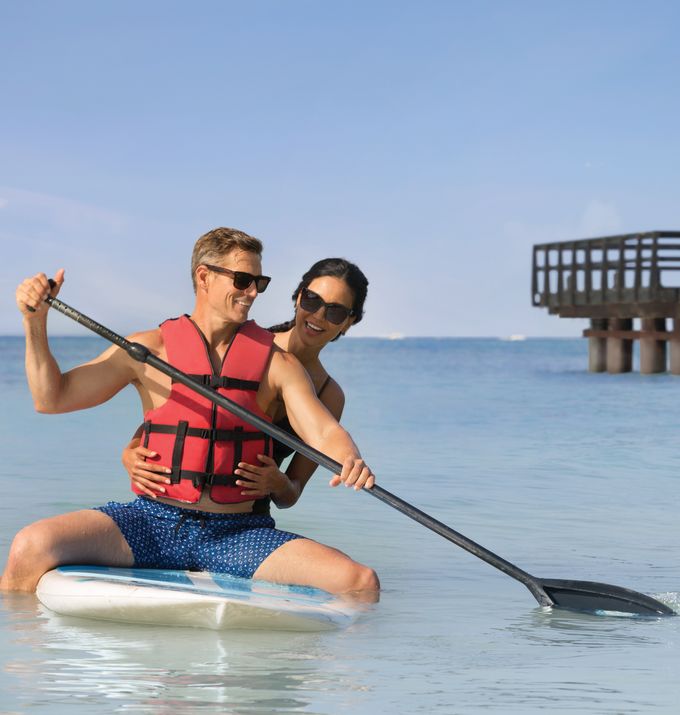 Man and woman in the sea, with paddle board